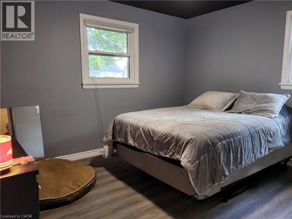 Room featuring wood-finish flooring, a white-framed window, and a dark ceiling - 33 Lee Avenue, Simcoe, ON
