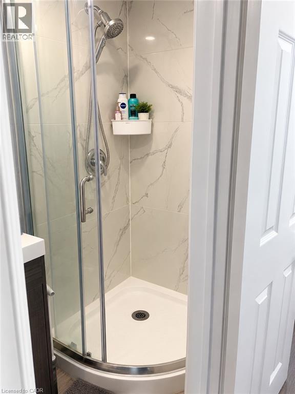 Corner shower enclosure with clear glass panels, a curved shower base, and a chrome shower head and fixtures - 73 Larkspur Crescent, Kitchener, ON