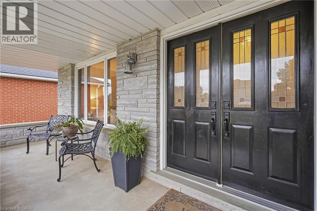 Double entry doors with decorative glass panels, stone facade, covered porch, and white framed windows - 76 Madeira Crescent, Cambridge, ON
