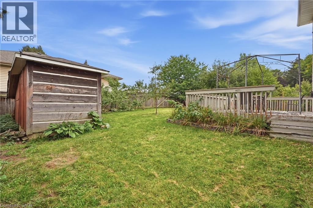 Expansive grassy yard featuring a wooden shed and a multi-level wooden deck - 76 Madeira Crescent, Cambridge, ON