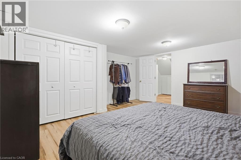 White walls, wood-finish flooring, flush mount lighting, and white bi-fold closet doors - 76 Madeira Crescent, Cambridge, ON