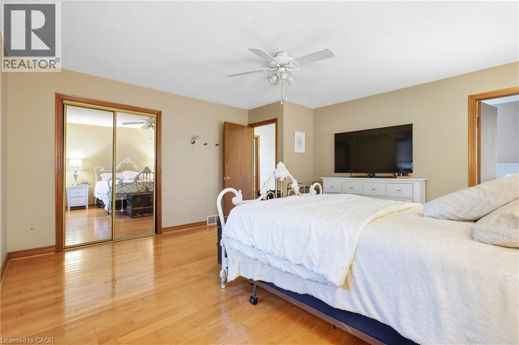 Hardwood flooring, mirrored closet doors, ceiling fan with integrated lighting, and neutral wall tones - 76 Madeira Crescent, Cambridge, ON