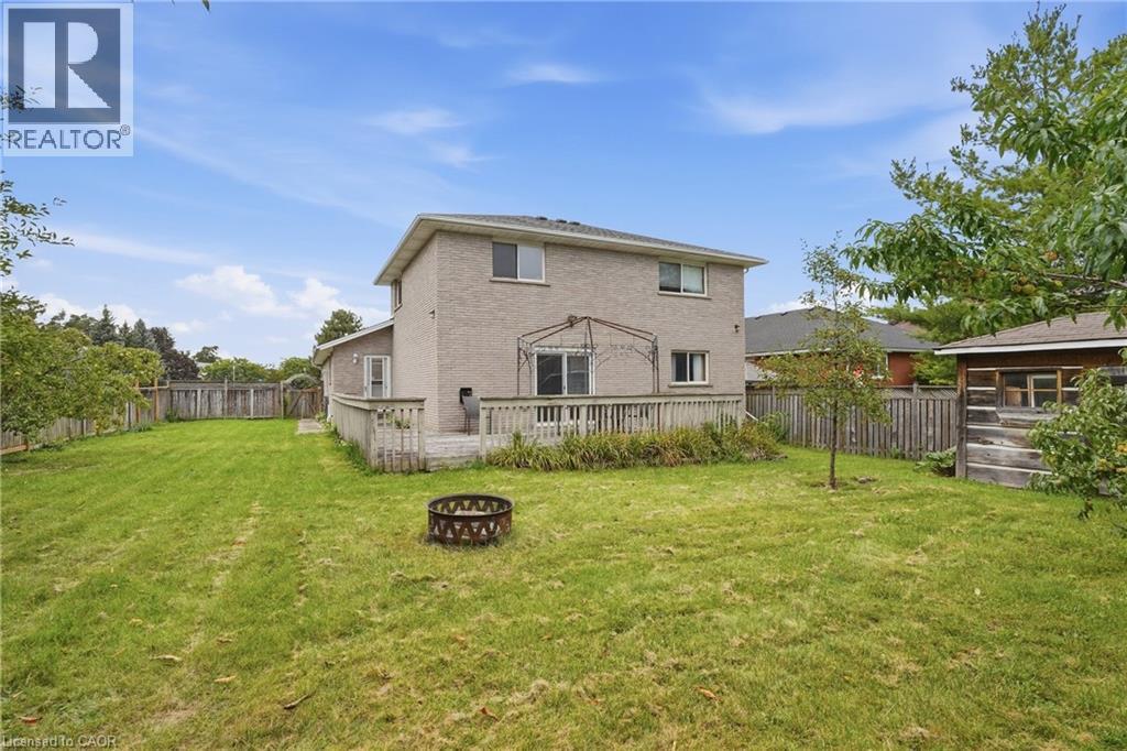 Expansive green lawn with mature trees and a wooden privacy fence - 76 Madeira Crescent, Cambridge, ON