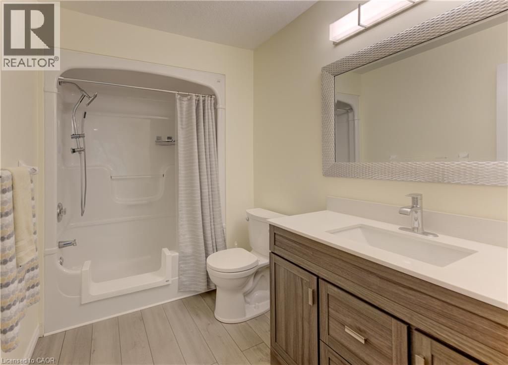 White vanity with integrated rectangular sink, gray wood-finish cabinetry, and brushed nickel hardware - 25 Bankside Drive Unit# 2, Kitchener, ON