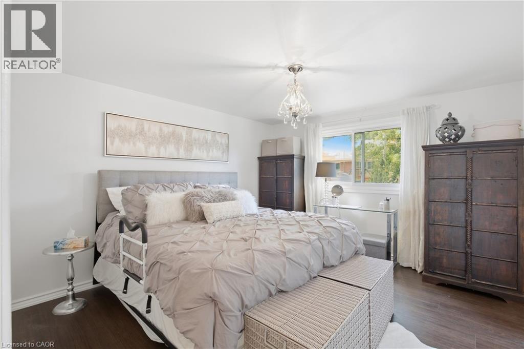 Hardwood-style flooring throughout, complemented by a large window with white trim - 22 Sycamore Street, Hamilton, ON
