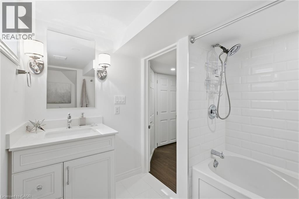 White shaker vanity with integrated sink, chrome faucet, and sconce lighting - 22 Sycamore Street, Hamilton, ON