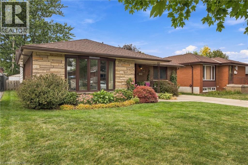 Brick and stone veneer exterior with a bay window, front lawn, and mature landscaping - 22 Sycamore Street, Hamilton, ON