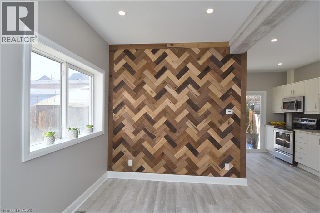 Herringbone wood-finish accent wall, recessed lighting, light wood-finish flooring, white trim, and white double-pane window - 76 Burlington Street E, Hamilton, ON