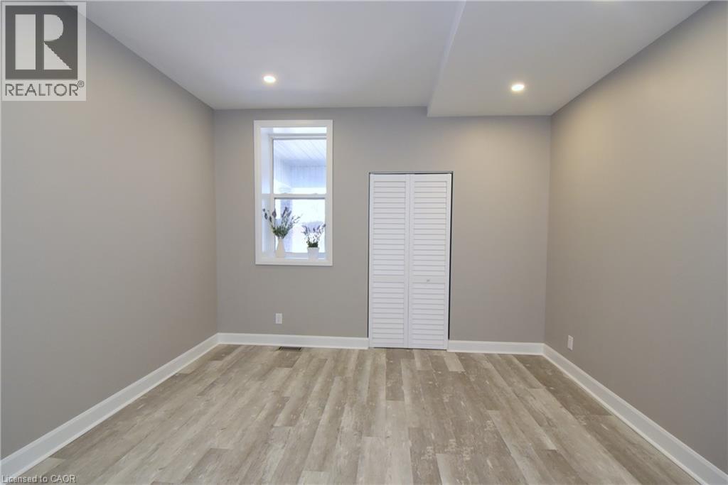 Recessed lighting, light gray wall finishes, wood-finish flooring, white window trim, and louvered bifold closet doors - 76 Burlington Street E, Hamilton, ON