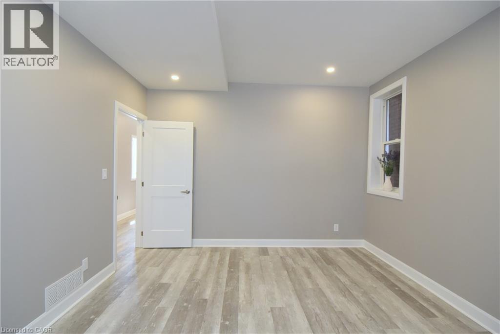 Recessed lighting, wood-finish flooring, neutral paint, white trim, and a window with white casing - 76 Burlington Street E, Hamilton, ON