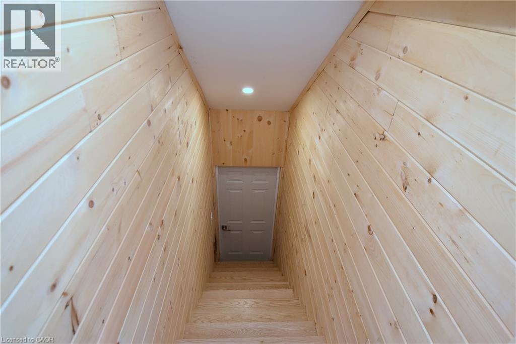 Wood-paneled walls with natural wood grain, recessed ceiling lighting, wood stairs, and a paneled door - 76 Burlington Street E, Hamilton, ON
