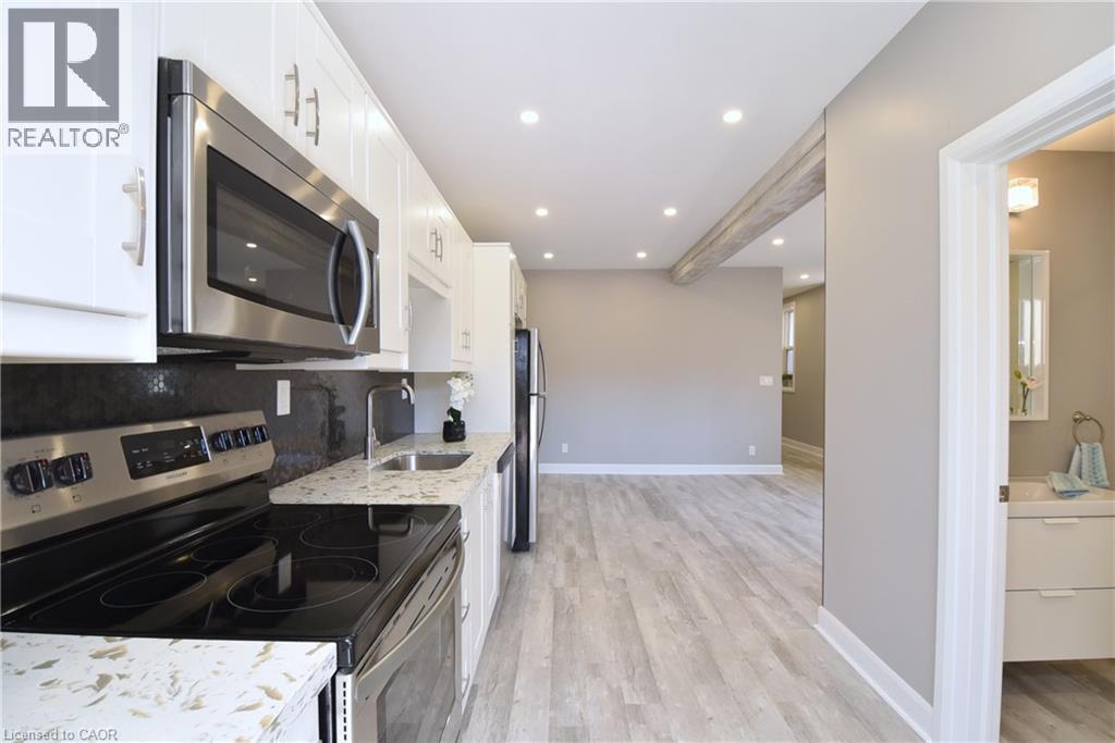Kitchen featuring white cabinetry, stainless steel appliances, speckled countertops, and recessed lighting - 76 Burlington Street E, Hamilton, ON