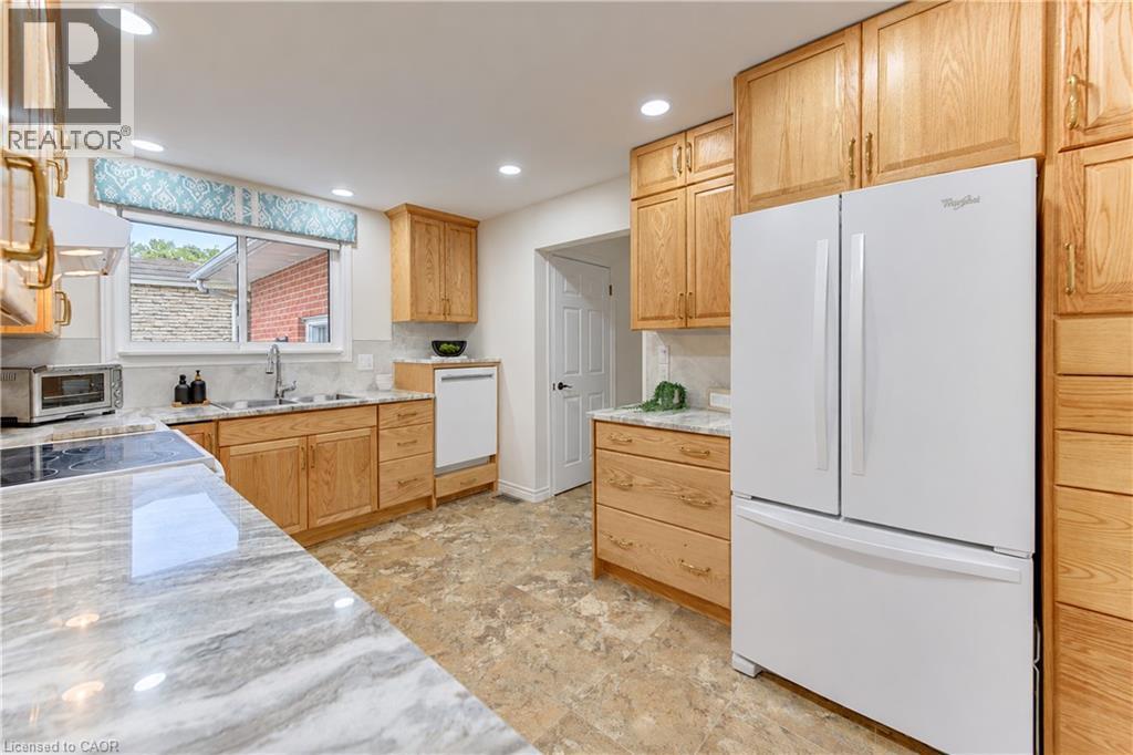 Full-height wood cabinetry, integrated white appliances, and light-toned countertops - 422 Grangewood Drive, Waterloo, ON