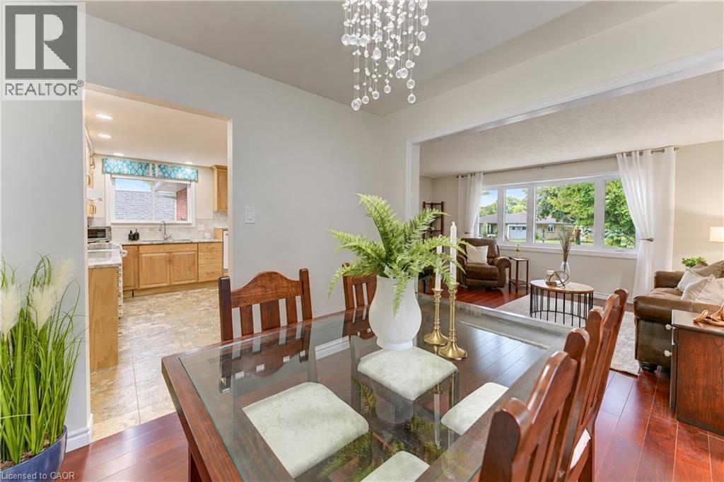 Dining area featuring a crystal chandelier, wood-finish flooring, and an open doorway to the kitchen - 422 Grangewood Drive, Waterloo, ON
