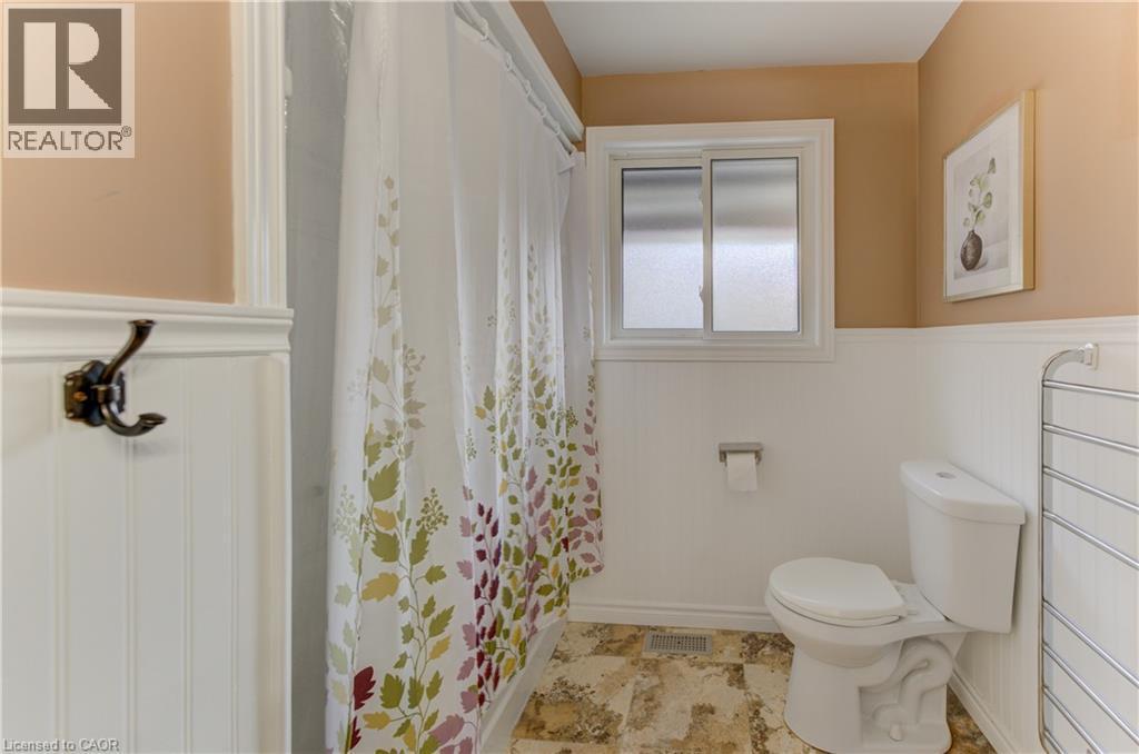 Beadboard wainscoting with a decorative trim, a single-pane sliding window, and a white toilet - 422 Grangewood Drive, Waterloo, ON