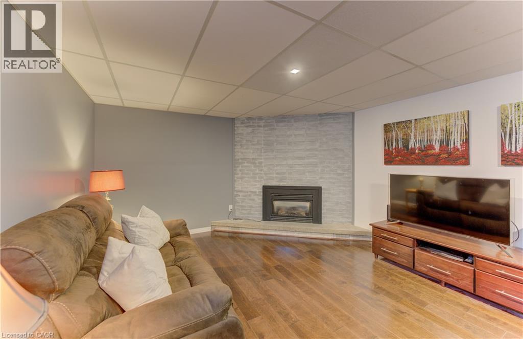 Hardwood-style flooring, a built-in fireplace with a stone surround, recessed lighting, and a drop ceiling - 422 Grangewood Drive, Waterloo, ON