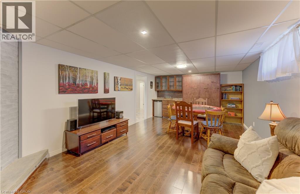 Wood-finish flooring throughout, recessed lighting, built-in shelving, and a wet bar with wood cabinetry - 422 Grangewood Drive, Waterloo, ON