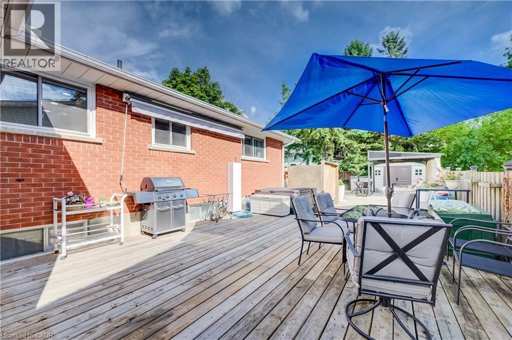Expansive wooden deck with brick exterior, featuring a built-in hot tub and a separate shed structure - 422 Grangewood Drive, Waterloo, ON