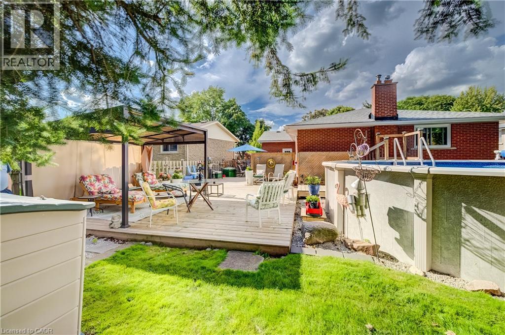 Expansive wood-finish deck with a built-in gazebo, complementing an above-ground pool with ladder access - 422 Grangewood Drive, Waterloo, ON