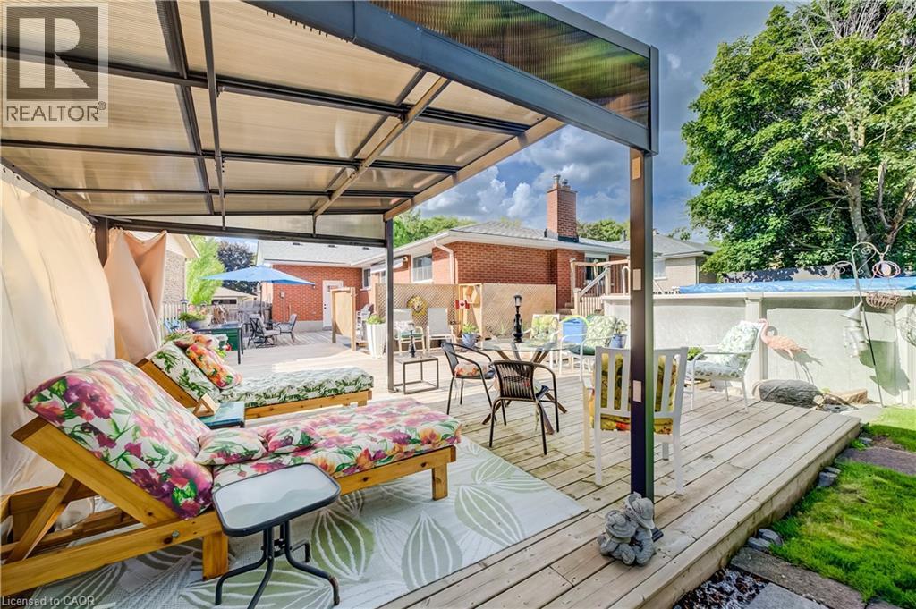 Patio featuring a metal-framed pergola with a translucent roof, a wooden deck, and a grass area - 422 Grangewood Drive, Waterloo, ON