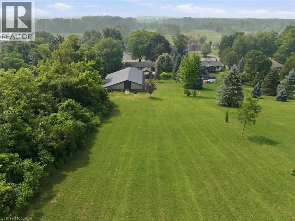 Expansive grassy lawn with mature trees and a detached structure featuring a metal roof - 1311 W Concession 6 Road, Flamborough, ON