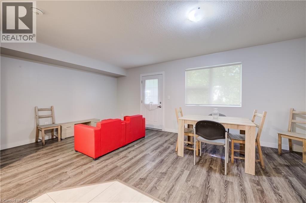Spacious room with wood-finish flooring, a white paneled door, and a large window with roller shades - 338 Albert Street Unit# 114, Waterloo, ON