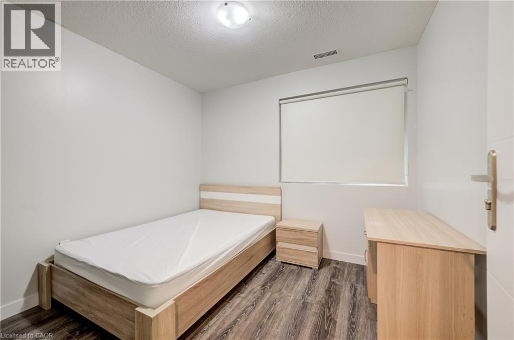 Wood-finish flooring, white walls, flush mount lighting, and a window with a roller shade - 338 Albert Street Unit# 114, Waterloo, ON