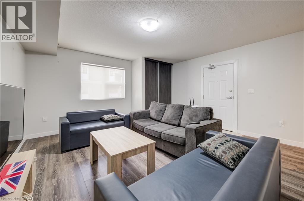 Room featuring wood-finish flooring, white walls, and a window with roller blinds - 338 Albert Street Unit# 114, Waterloo, ON