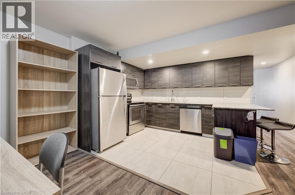 Kitchen with stainless steel appliances, dark wood-finish cabinetry, light-toned countertop, and recessed lighting - 338 Albert Street Unit# 114, Waterloo, ON