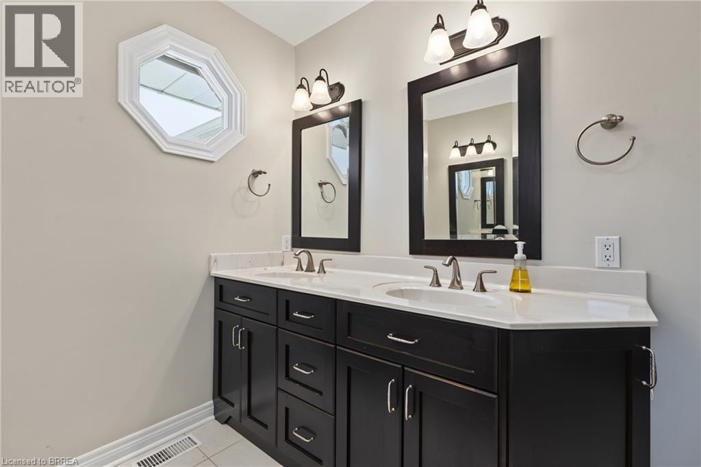 Dual vanity with dark wood-finish cabinetry, integrated sinks, and polished chrome fixtures - 141 Race Street, Paris, ON
