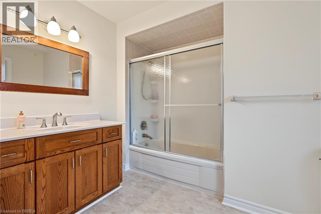 Wood-finish vanity with an integrated basin, brushed nickel faucet, and a framed mirror - 141 Race Street, Paris, ON