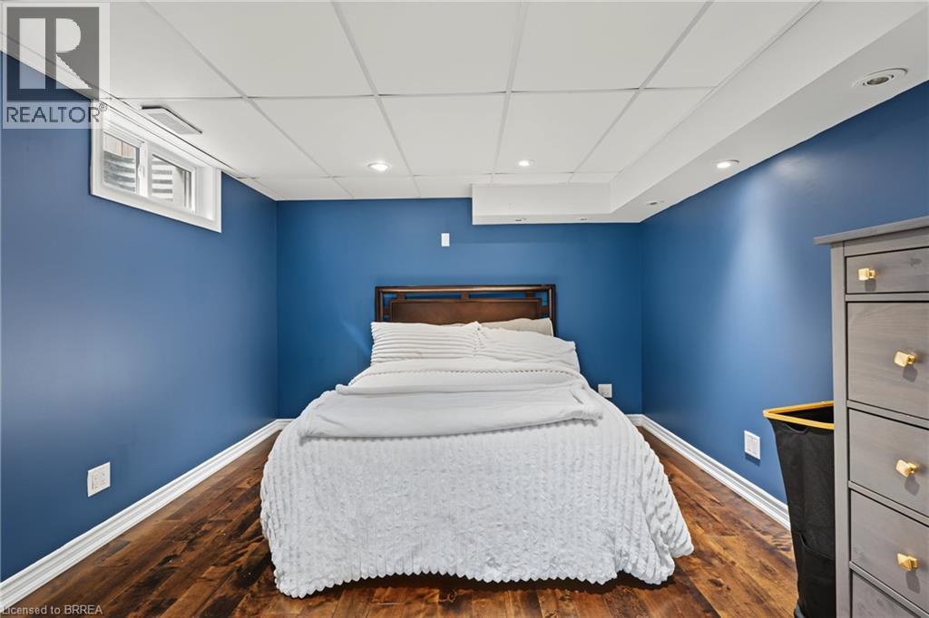 Wood-finish flooring, drop ceiling with recessed lighting, and a single window with white trim - 141 Race Street, Paris, ON
