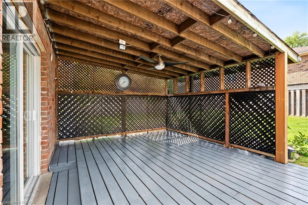Covered outdoor deck with painted wood flooring, exposed wood beam ceiling, and lattice privacy screens - 141 Race Street, Paris, ON