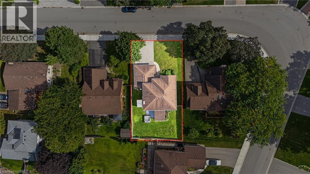 Aerial property outline encompassing a residence with a light brown shingled roof, a paved driveway, and manicured lawns - 141 Race Street, Paris, ON