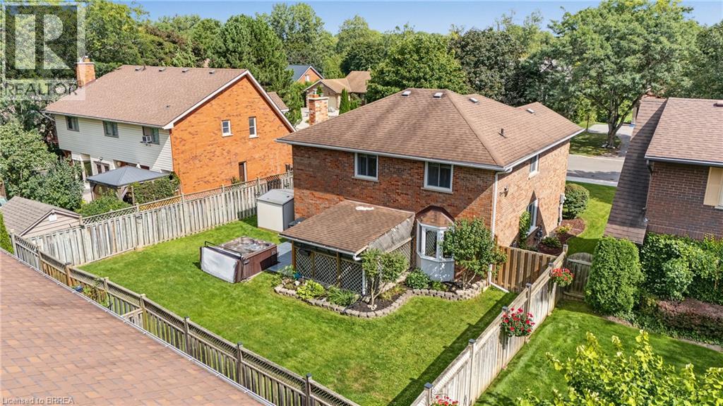 Brick exterior with a peaked roof, manicured lawn, and wood privacy fencing - 141 Race Street, Paris, ON