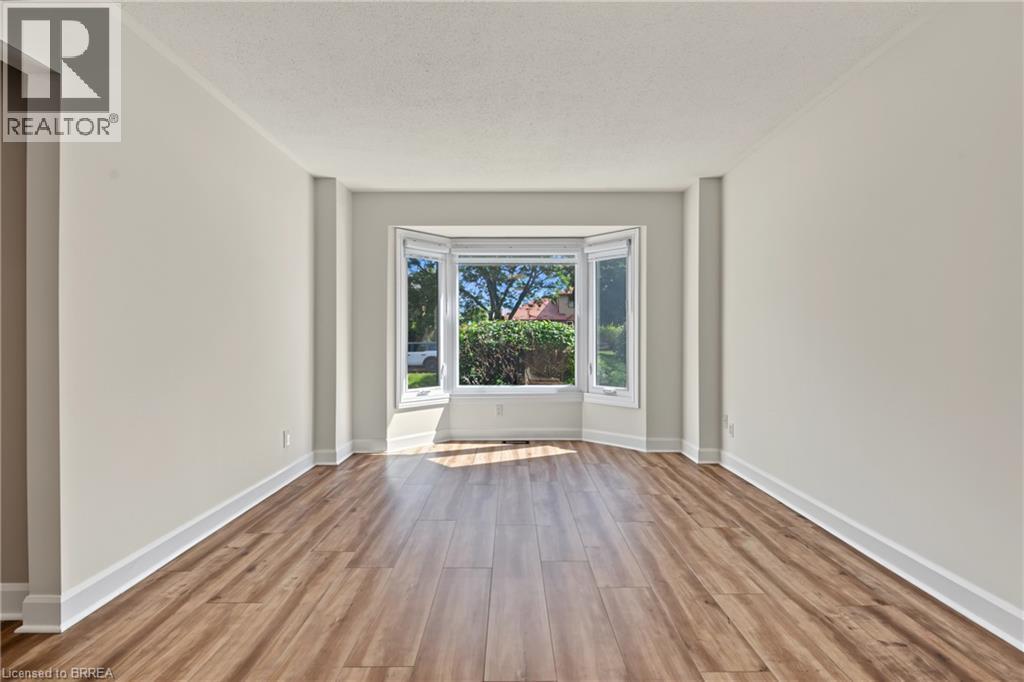 Spacious room featuring wood-finish flooring, light-toned walls, and a prominent bay window - 141 Race Street, Paris, ON
