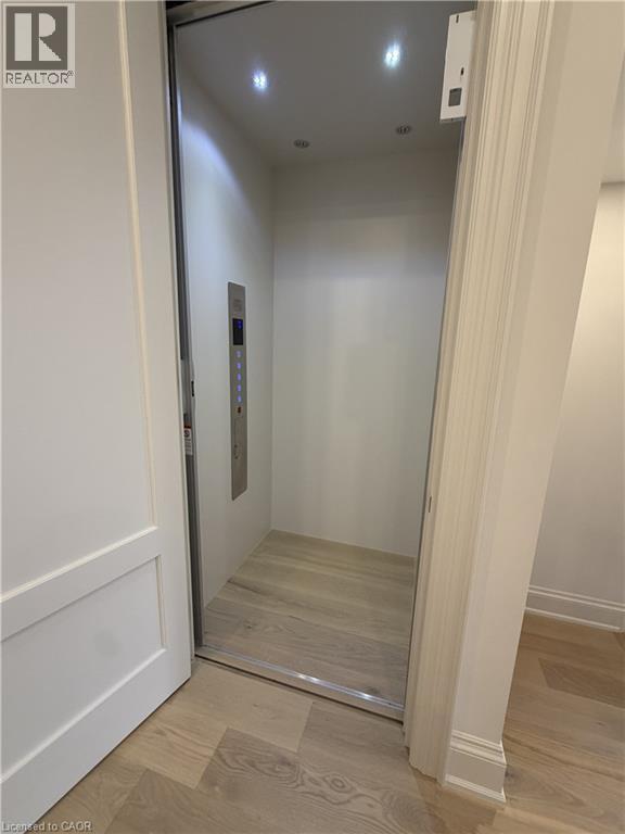Private elevator with recessed lighting, wood-finish flooring, and a stainless steel control panel - 335 Helen Lawson Lane, Oakville, ON