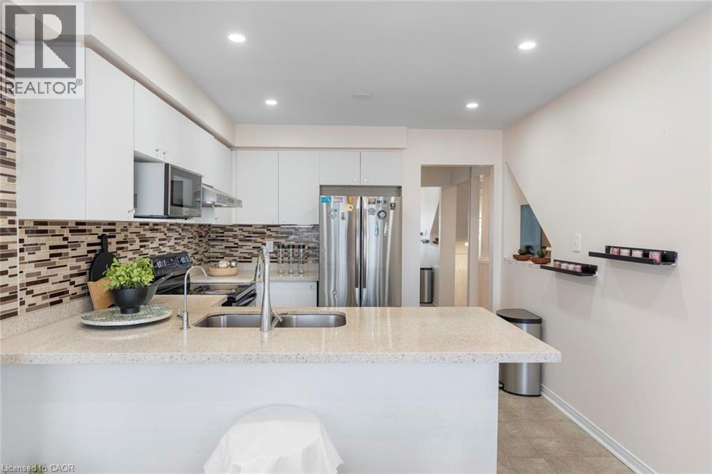Modern kitchen featuring white cabinetry, a light-toned countertop, a tile backsplash, stainless steel appliances, and recessed lighting - 123 Brickyard Way, Brampton, ON