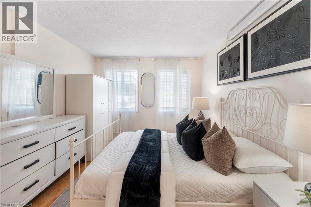 Bright bedroom featuring dual windows, light-toned walls, and wood-finish flooring - 123 Brickyard Way, Brampton, ON
