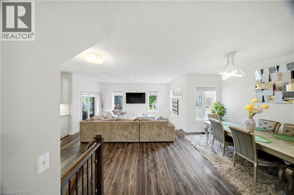 Spacious interior featuring wood-finish flooring, recessed lighting, a contemporary dining fixture, and multiple windows - 167 Broadoaks Drive, Cambridge, ON