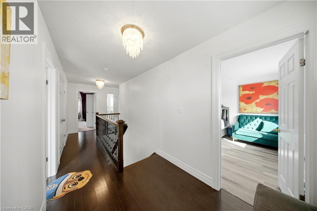 Hallway featuring dark wood-finish flooring, white walls, and decorative ceiling-mounted light fixtures - 167 Broadoaks Drive, Cambridge, ON