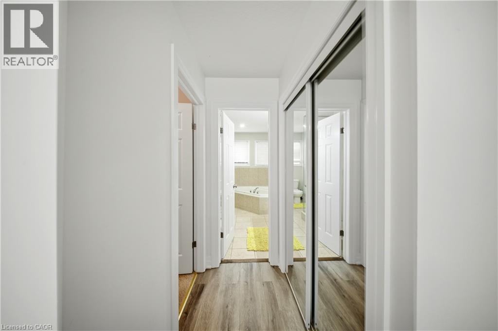 Hallway with wood-finish flooring, white walls, and a mirrored closet door - 167 Broadoaks Drive, Cambridge, ON
