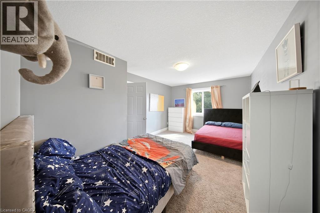 Carpeted bedroom featuring a window with natural light, a ceiling-mounted light fixture, and a white interior door - 167 Broadoaks Drive, Cambridge, ON