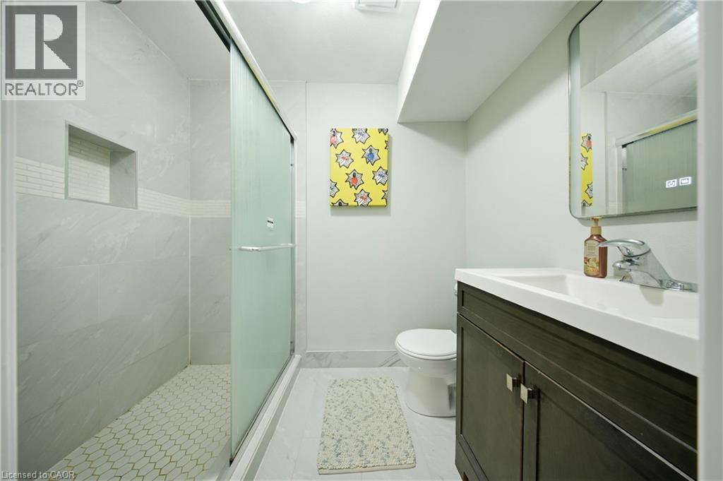 Walk-in shower with sliding glass door, white hexagonal tile flooring, and integrated shower niche - 167 Broadoaks Drive, Cambridge, ON