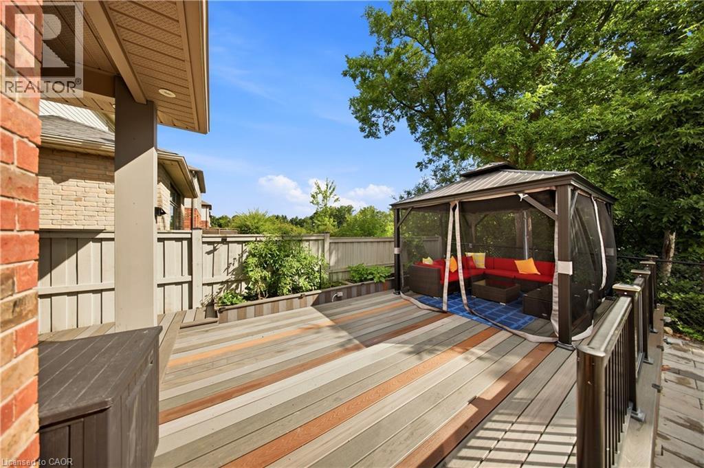 Multi-tone wood-finish deck with built-in storage bench, a screened gazebo, and wood fencing - 167 Broadoaks Drive, Cambridge, ON
