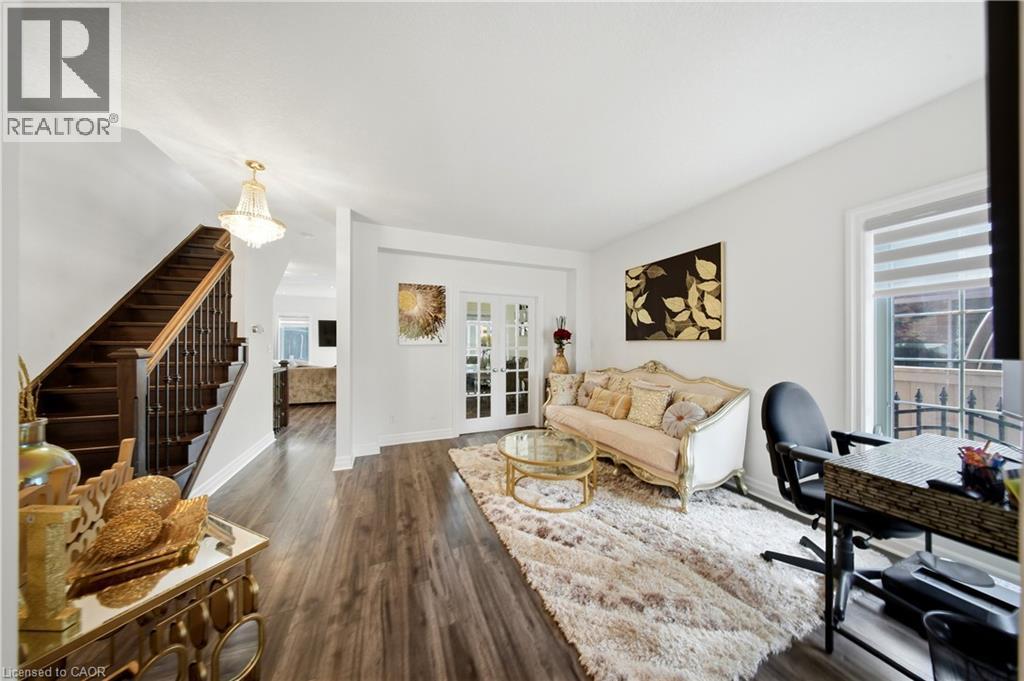 Wood-finish flooring throughout, a traditional wood staircase with wrought iron spindles, double French doors, and a decorative chandelier - 167 Broadoaks Drive, Cambridge, ON