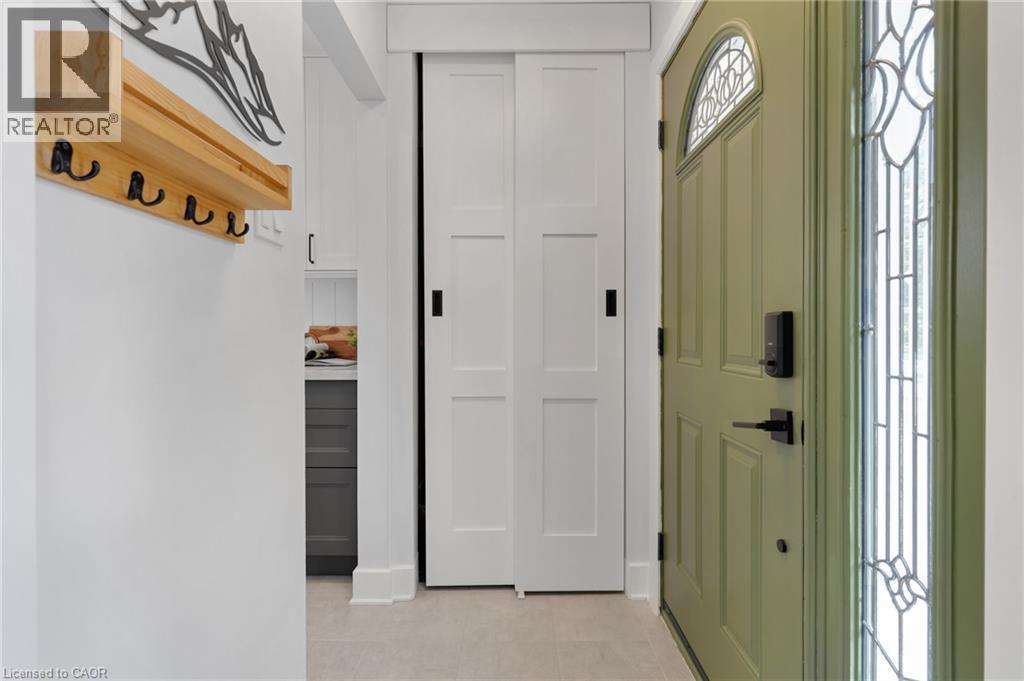 Sage green entry door with arched transom window, leaded glass sidelight, bi-fold panel doors, and tile flooring - 477 Kingscourt Drive Unit# B, Waterloo, ON