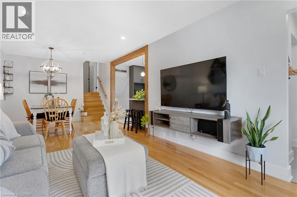 Open-concept living area featuring hardwood flooring, recessed lighting, a modern chandelier, and a built-in media console - 477 Kingscourt Drive Unit# B, Waterloo, ON