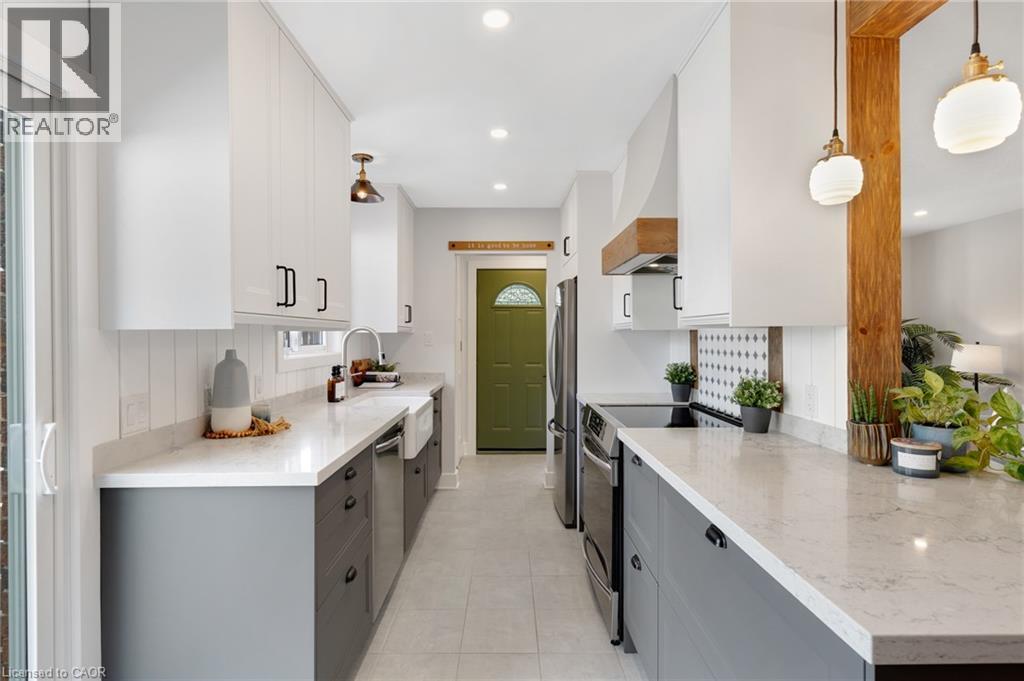 Two-tone cabinetry with white upper and gray lower cabinets, light-toned countertops, recessed and pendant lighting, and stainless steel appliances - 477 Kingscourt Drive Unit# B, Waterloo, ON