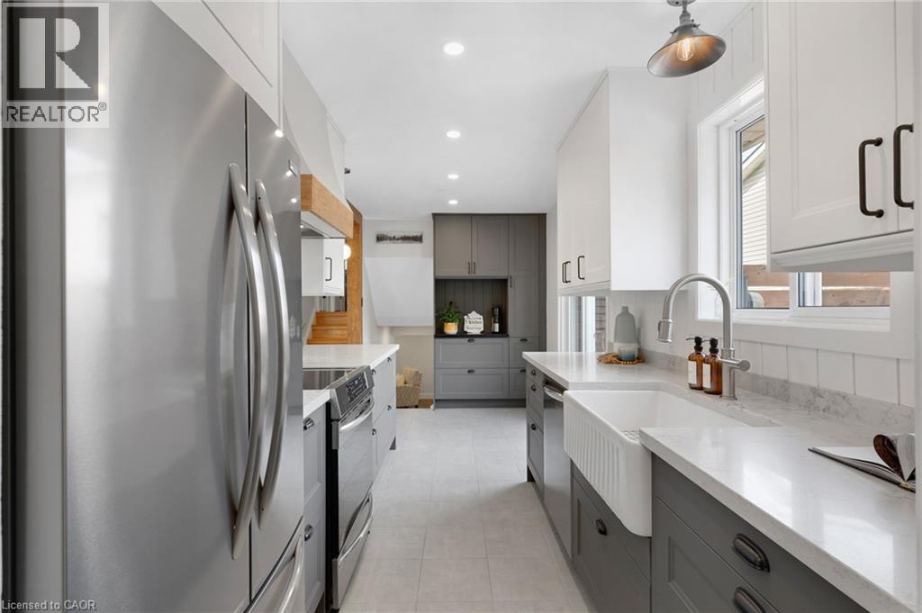 Stainless steel appliances, white apron-front sink, white upper cabinetry, gray lower cabinetry, and recessed ceiling lighting - 477 Kingscourt Drive Unit# B, Waterloo, ON